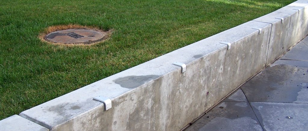 Row of skate stoppers along a long concrete ledge in a park